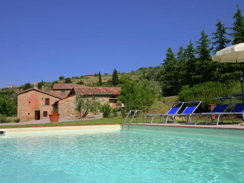 une piscine avec des chaises bleues et une maison dans l'établissement Belvilla by OYO Fontocchio, à Cortone