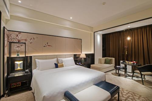 a bedroom with a large white bed and a desk at Rainbird Hotel in Chengdu