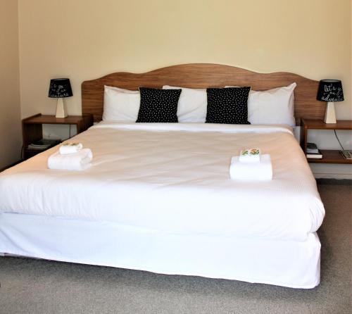 a bedroom with a large white bed with two towels on it at Owen River Tavern & Motels in Owen River