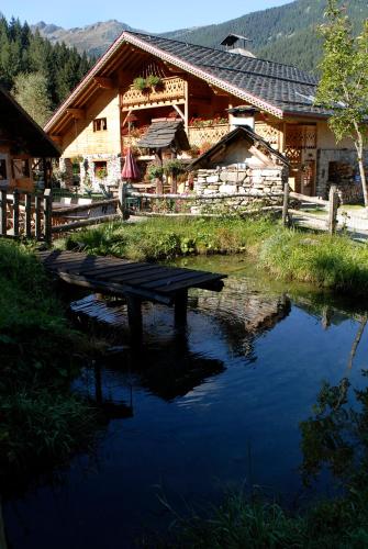 a log cabin with a pond in front of it at Auberge NEMOZ in La Ferrière
