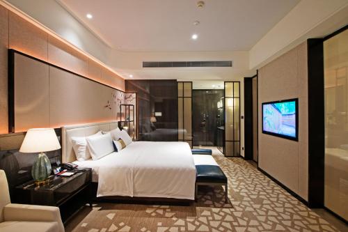 a hotel room with a bed and a television at Rainbird Hotel in Chengdu
