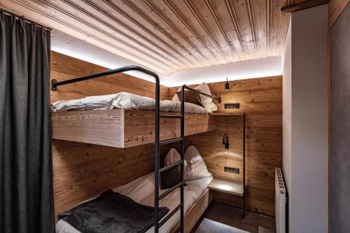 two bunk beds in a room with wooden walls at Alpin View in Zellberg