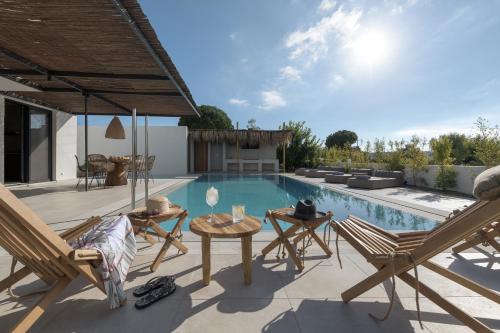 a swimming pool with chairs and a table and a patio at Bianco Villa - Adam in Pefki