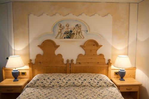 a bedroom with a large bed with two lamps at Hotel Sassongher in Corvara in Badia