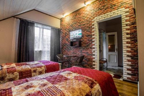 a bedroom with two beds and a brick wall at Садиба Вікторія in Morshin