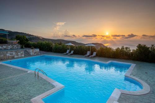 a swimming pool with a sunset in the background at Niforos Panorama in Vovikes