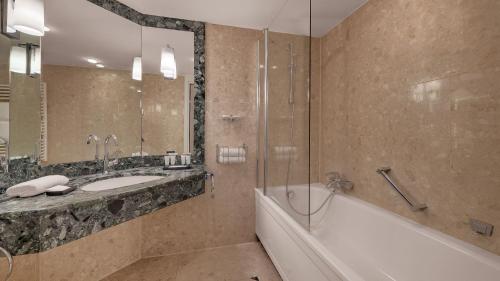 a bathroom with a tub and a sink and a bath tub at Bilderberg Bellevue Hotel Dresden in Dresden