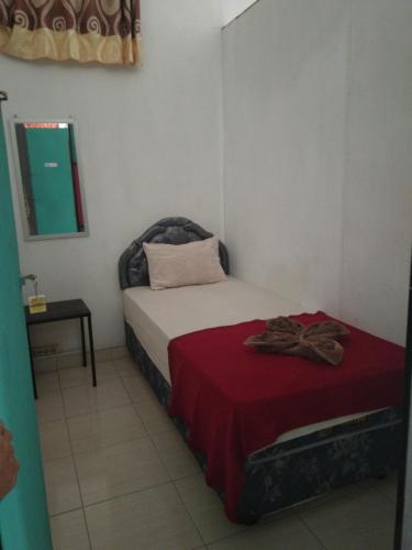 a small bedroom with a bed with a red blanket at Dasi Guesthouse in Ende