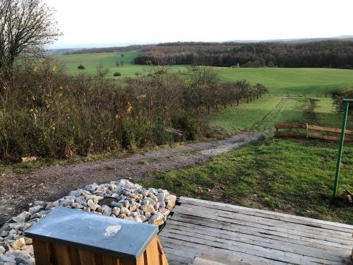 a wooden deck with a pile of rocks next to a field at Sunrise Cabin et Sauna in Rothbach