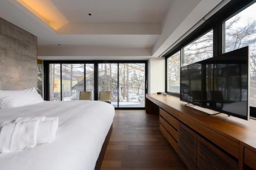 - une chambre avec un grand lit et une télévision à écran plat dans l'établissement Sekka Sekka, à Niseko