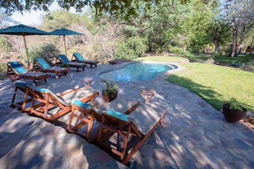 Un grupo de sillas junto a una piscina. en Ku Sungula Safari Lodge, en Balule Game Reserve