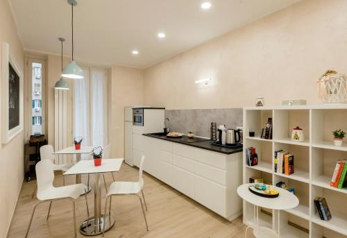una cucina con armadi bianchi, tavolo e sedie di Le vestali Guest House a Roma