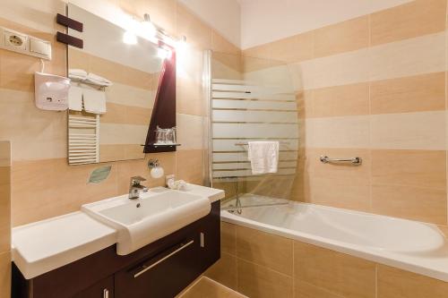 a bathroom with a sink and a bath tub at Hotel Aurum in Hajdúszoboszló