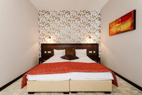 a bedroom with a bed with a red bedspread at Hotel Aurum in Hajdúszoboszló