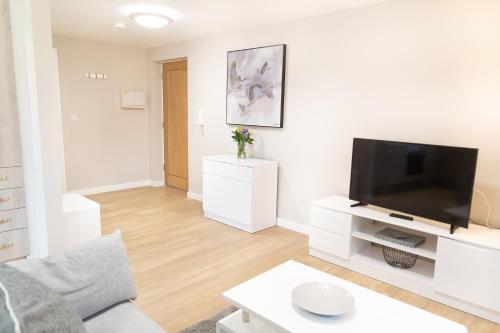 a white living room with a flat screen tv at Citystay Living - Hinton House in Cambridge