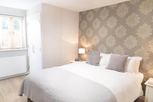 a bedroom with a white bed and a wall at Citystay Living - Hinton House in Cambridge