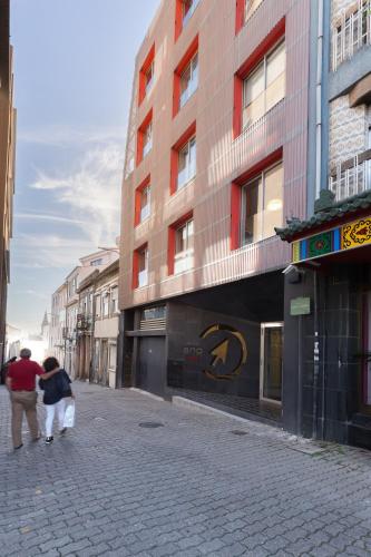 a man and a woman walking down a street at QP Trindade Apartments in Porto