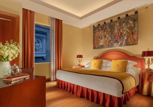 a bedroom with a bed, a desk and a painting on the wall at Bio Hotel Raphael - Relais & Châteaux in Rome