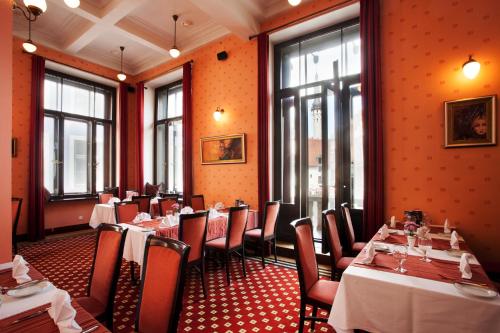 un restaurante con mesas y sillas en una sala con paredes de color naranja en Hestia Hotel Barons Old Town, en Tallin
