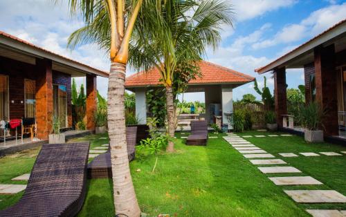 a palm tree in front of a house with benches at Umah Nugraha in Canggu