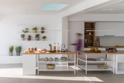 a kitchen with white cabinets and a table with plants at The Saint Hotel in Oia