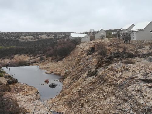 a view of a hill with houses and a river at Munsterland Guest Farm in Outjo