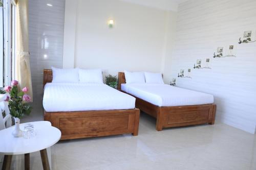 two twin beds in a room with a table at Da Lat Ngoi Sao Viet in Da Lat