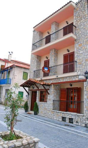 un gran edificio de piedra con un árbol delante de él en Sfaragoulias Inn en Kalavrita
