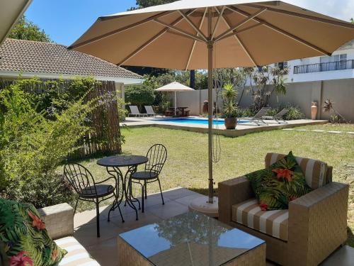 a patio with an umbrella and a table and chairs at Cottage@Somerset in Somerset West