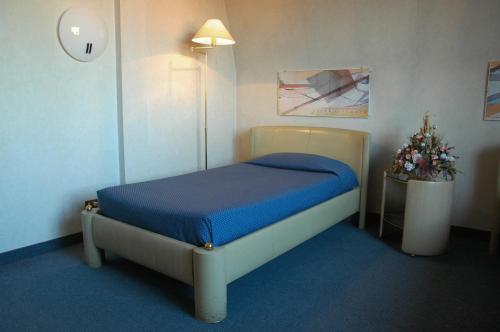 a bedroom with a bed with blue sheets and a lamp at Hotel Lincoln in Cinisello Balsamo