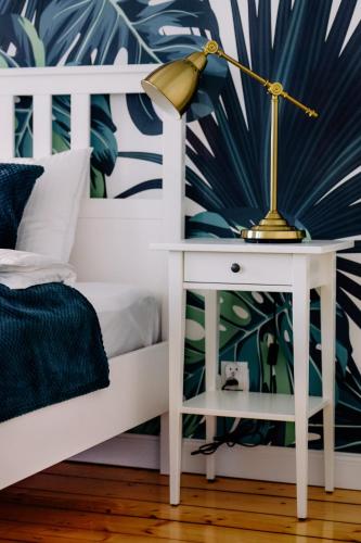 a bed with a white bedside table and a lamp on a night stand at Staszica16 in Złoty Stok