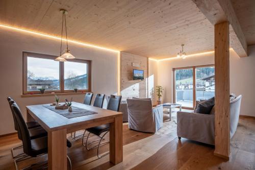 una sala da pranzo e un soggiorno con tavolo e sedie di Alpenchalet "DAHOAM" a Going