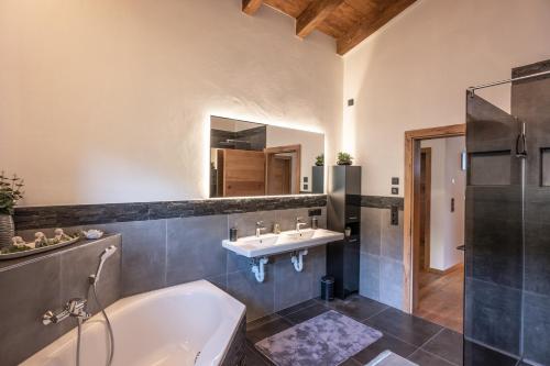 un bagno con vasca e lavandino di Alpenchalet "DAHOAM" a Going