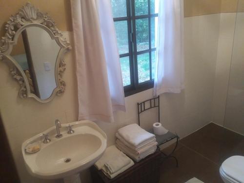 ein Badezimmer mit Waschbecken, Spiegel und Fenster in der Unterkunft Estancia La Dulce - Casa de huespedes in Roque Pérez