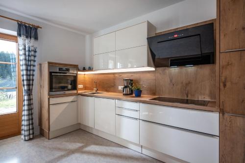 a kitchen with white cabinets and a sink and a microwave at Chalet Glücklich sein... in Ellmau
