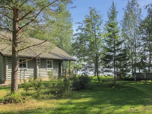 a log cabin in a yard with trees at Holiday Home Tuulikannel by Interhome in Hillilä