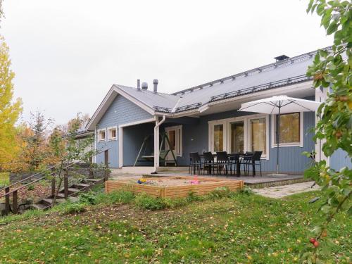 a blue house with a table and chairs and an umbrella at Holiday Home Villa lehmus by Interhome in Rovaniemi