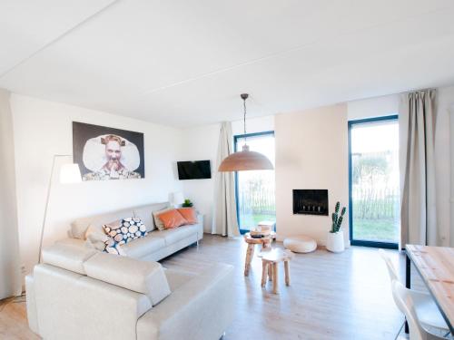 a white living room with a couch and a table at Holiday Home Oesterdam Resort-1 by Interhome in Tholen