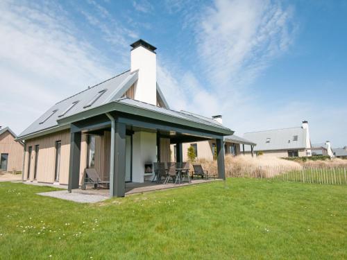 a house with a pitched roof with a patio at Holiday Home Oesterdam Resort-1 by Interhome in Tholen