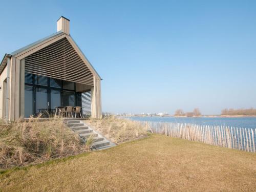a small house on the shore of a body of water at Holiday Home Oesterdam Resort-1 by Interhome in Tholen