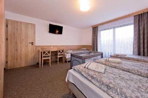 a hotel room with four beds and a table at Pokoje Gościnne Kornelia- Jacuzzi, sauna ! in Biały Dunajec