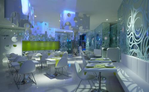 a restaurant with white tables and white chairs at i-Suite Hotel in Rimini