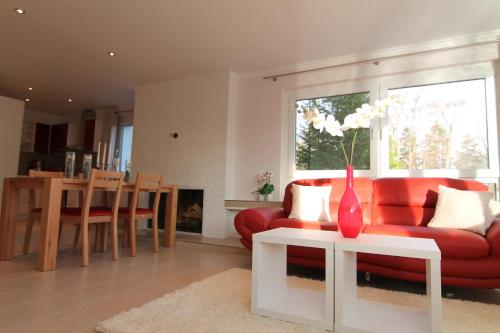 a living room with a red couch and a vase on a table at Der Buchenhof in Braunlage