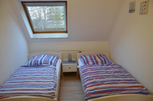 two beds in a small room with a window at Aquamarin in Dahme