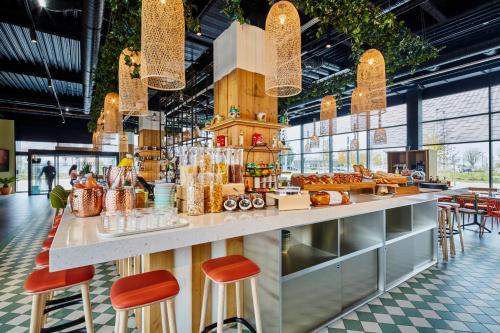 a restaurant with stools and a counter with pastries at Mercure Paris Orly Airport in Orly