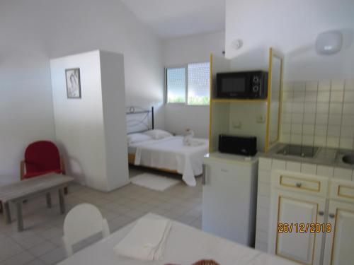 a room with a kitchen and a bedroom with a bed at BALAGA ocarina in Sainte-Anne
