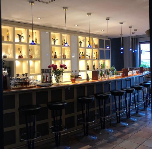 a bar with stools in a restaurant with lights at Hotel ARTE Schwerin in Schwerin