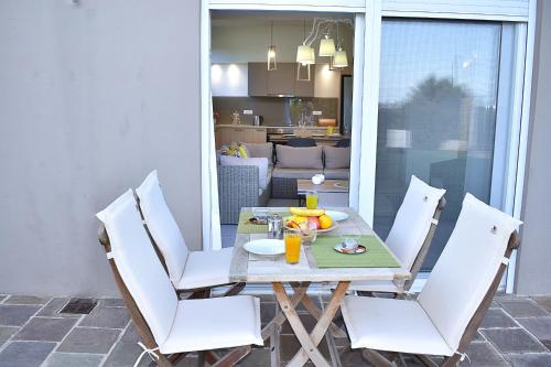 a dining table with white chairs in a kitchen at Modi Home in Vrísai