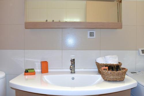 a bathroom sink with a mirror and a basket on it at Modi Home in Vrísai
