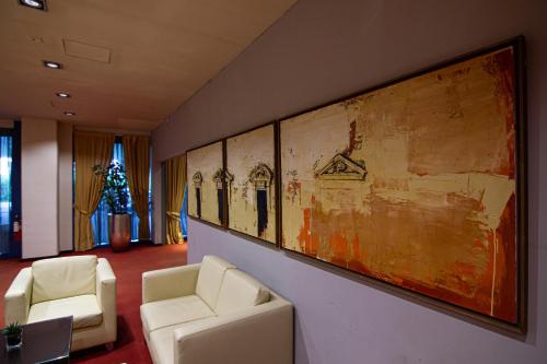 a living room filled with furniture and paintings at Tuscany Inn in Montecatini Terme